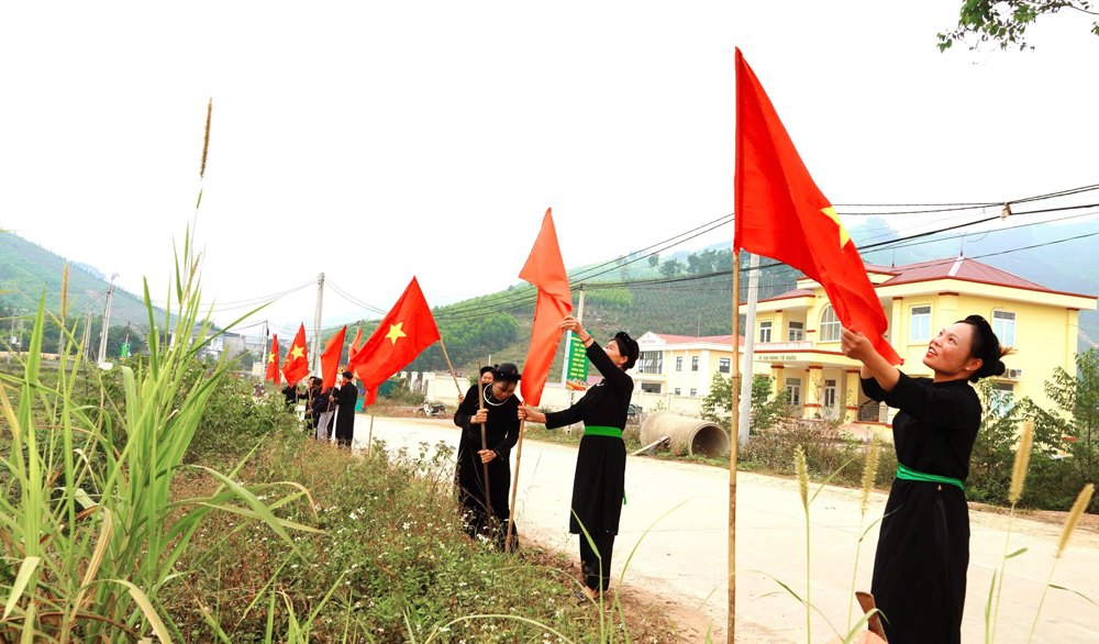 Người dân bản Nà Ó, xã An Lạc trang trí cờ dọc tuyến đường thôn để chào đón năm mới. Ảnh: Xuân Thoả