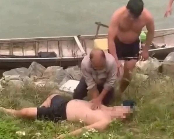 Thầy giáo Thảo (người đang đứng) cùng một người dân hô hấp, cứu sống nạn nhân. Ảnh: Cắt từ clip
