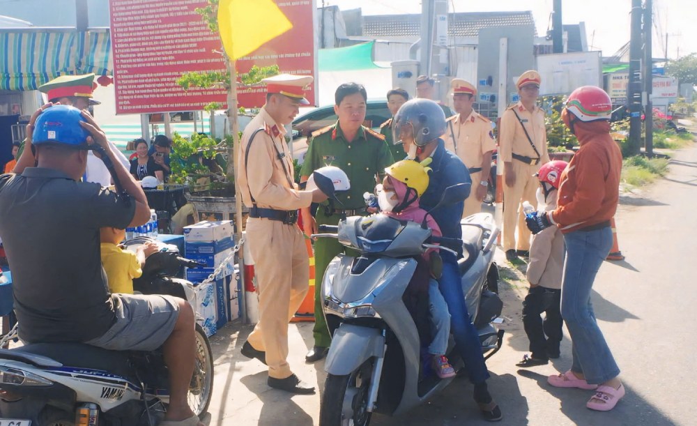 Tặng nón bảo hiểm, phát nước suối miễn phí cho người dân. Ảnh: Công an An Giang