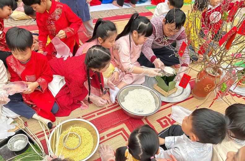 Học sinh Trường Tiểu học Tây Tựu A (Hà Nội) tham gia gói bánh chưng - hoạt động không thể thiếu vào mỗi dịp Tết đến. Ảnh: Nhà trường cung cấp 