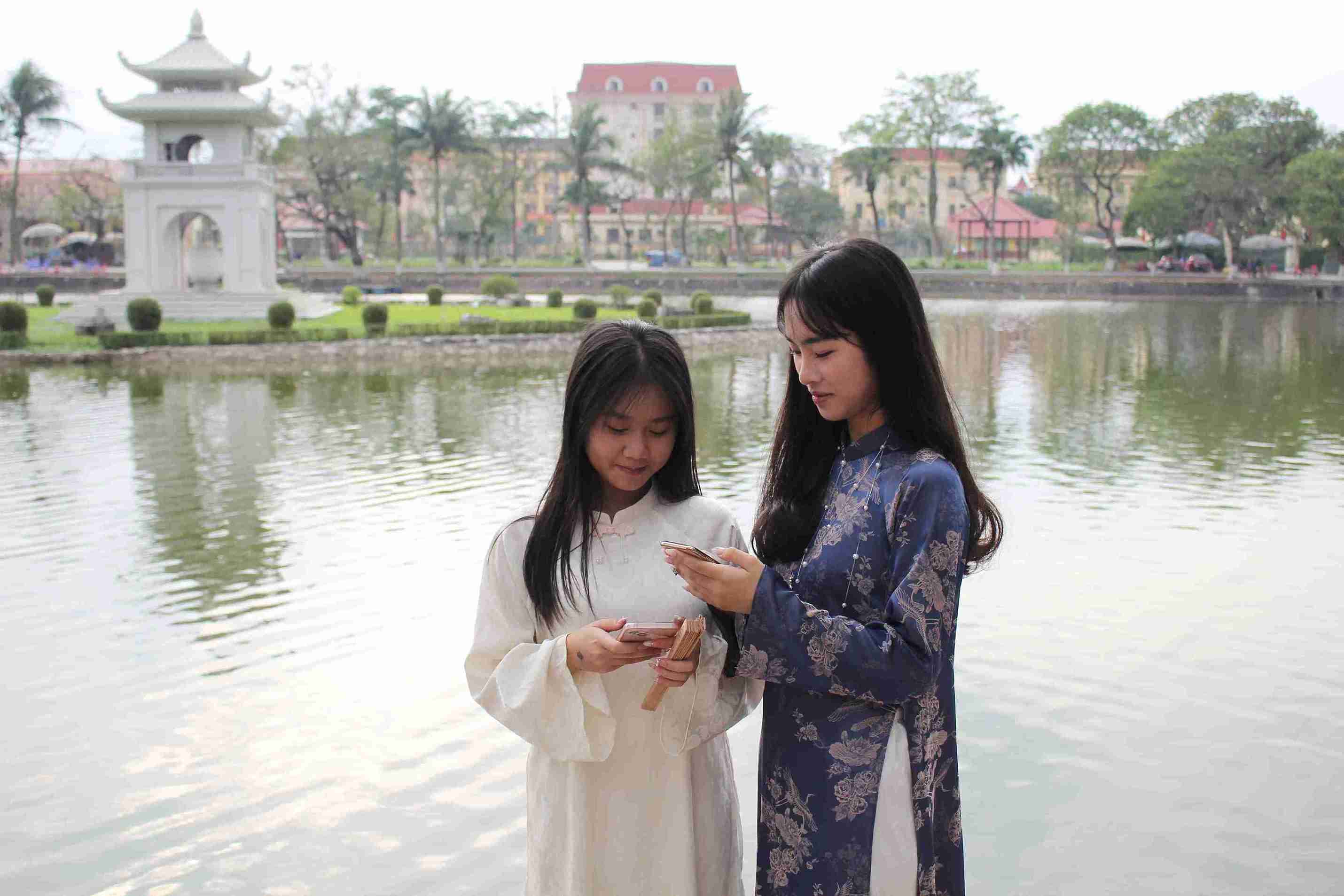 Hai bạn trẻ xem lại hình ảnh vừa chụp tại khu vực đường hoa Hồ Bán Nguyệt.