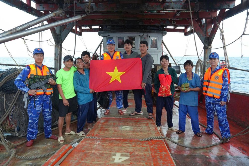 Officers and soldiers of Coast Guard Vessel 8005, Naval Flotilla 42, Coast Guard Region 4 Command present national flags and Tet gifts to fishermen to add motivation to feel secure in going offshore and sticking to the sea. Photo: Thai Trung