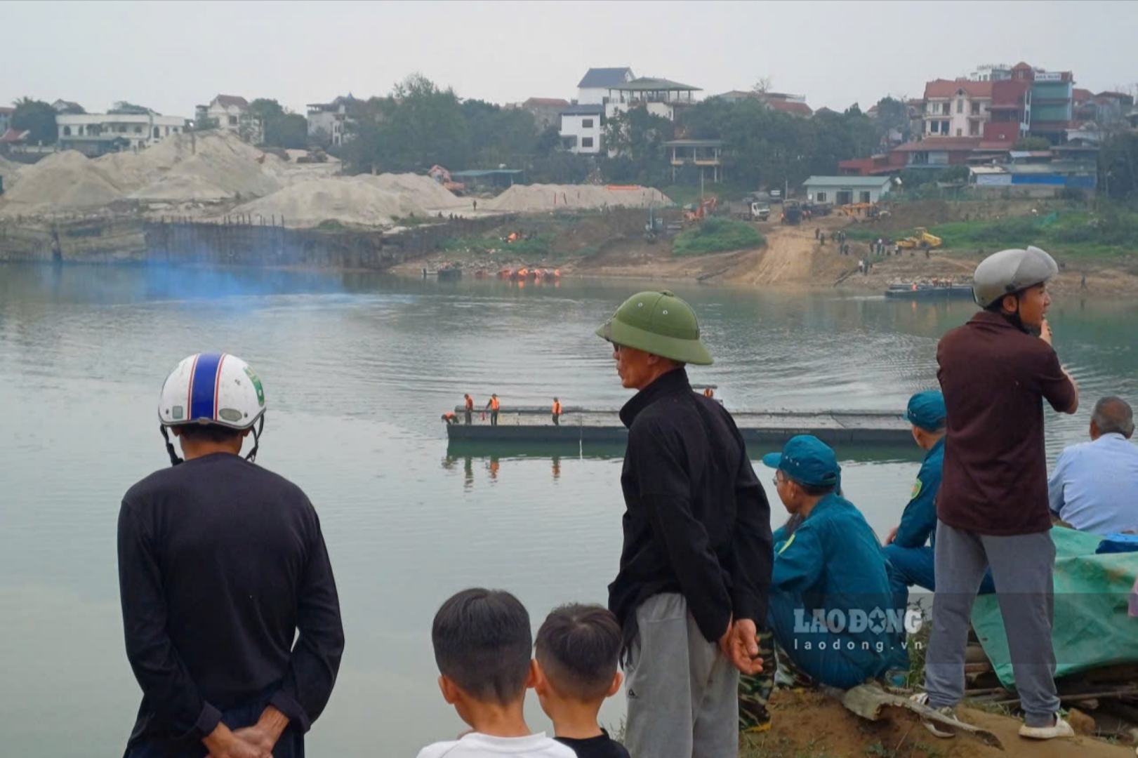 Từ sáng sớm, người dân xã Đoan Hùng đã ra bờ sông xem bộ đội lắp đặt cầu phao. Ảnh: Tô Công.