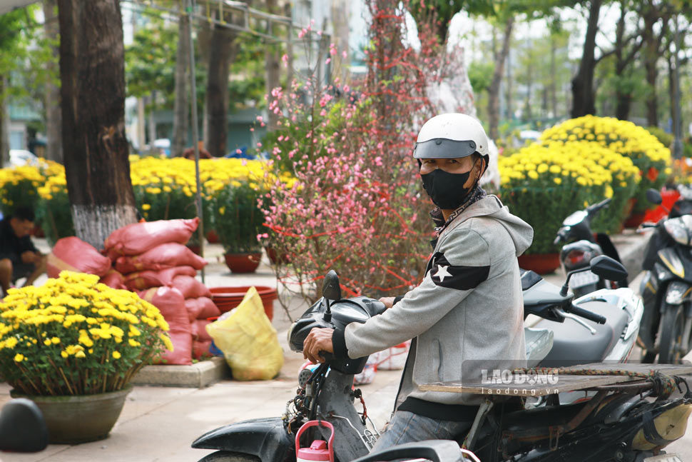 Lao động tự do tranh thủ nhận giao hoa Tết để kiếm thêm thu nhập. Ảnh Hoài Phương