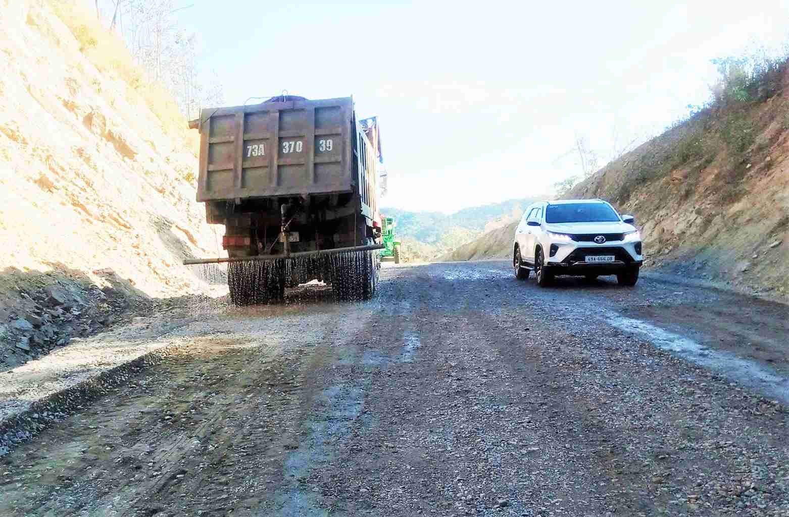 Đơn vị thi công tưới nước chống bụi đoạn đường vừa được khắc phục trên Quốc lộ 28B. Ảnh: Hải Đường