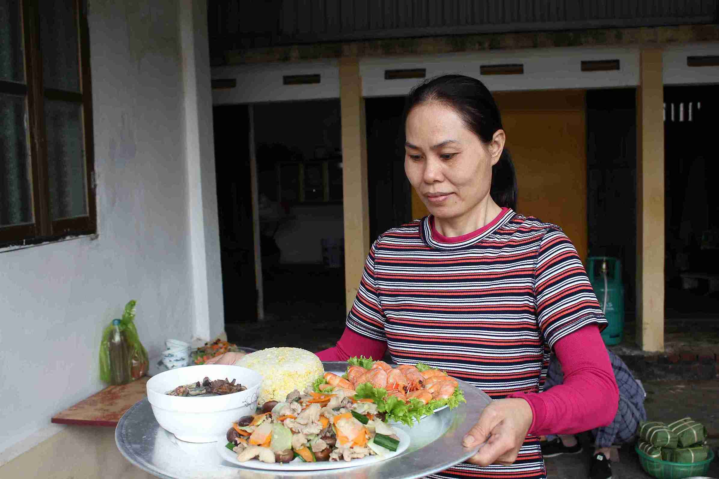 Ms. Dao Thi Thinh carries a tray of rice to offer incense to her ancestors on the last day of the year. Photo: Mai Huong