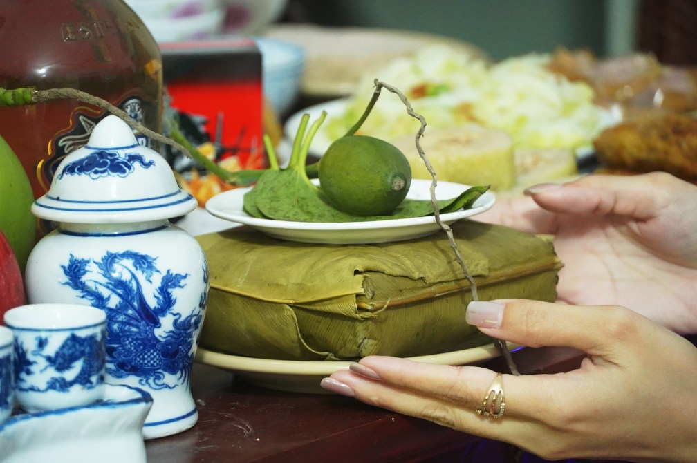 Chị Yến Phương trang trọng đặt chiếc bánh chưng do chính tay mình gói lên mâm cỗ cúng giao thừa. Ảnh: Tạ Quang