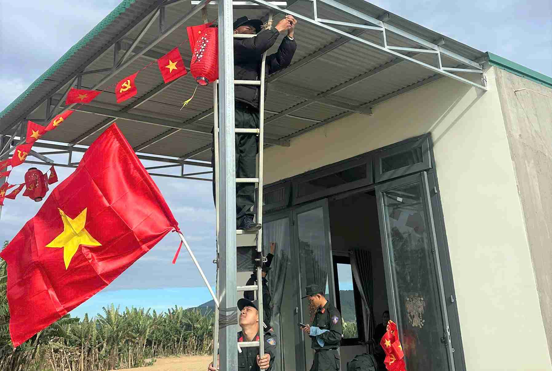 Cán bộ, chiến sĩ Công an Lâm Đồng treo cờ Tổ quốc, giúp người dân rộn ràng đón Tết. Ảnh: Thần Hy