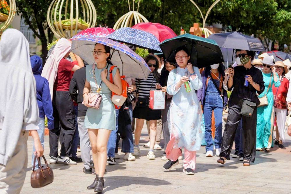 Nền nhiệt tại TP.HCM trong ngày đầu năm duy trì ở mức cao, dao động khoảng 30 độ C, nhiệt độ cảm nhận thực tế ngoài trời có thể lên tới 32-33 độ C. Cái nắng gay gắt giữa trưa khiến không ít du khách, đặc biệt là phụ nữ và trẻ em, phải trang bị kín mít ô, nón, quạt cầm tay và lộ rõ vẻ mệt mỏi trên khuôn mặt.