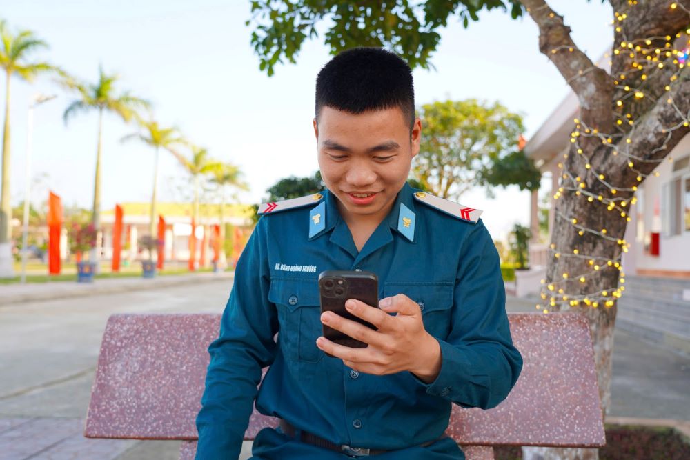 Hạ sĩ Nguyễn Đăng Hoàng Thương tranh thủ thời gian nghĩ ngơi gọi điện về chúc Tết gia đình. Ảnh: Thanh Trung