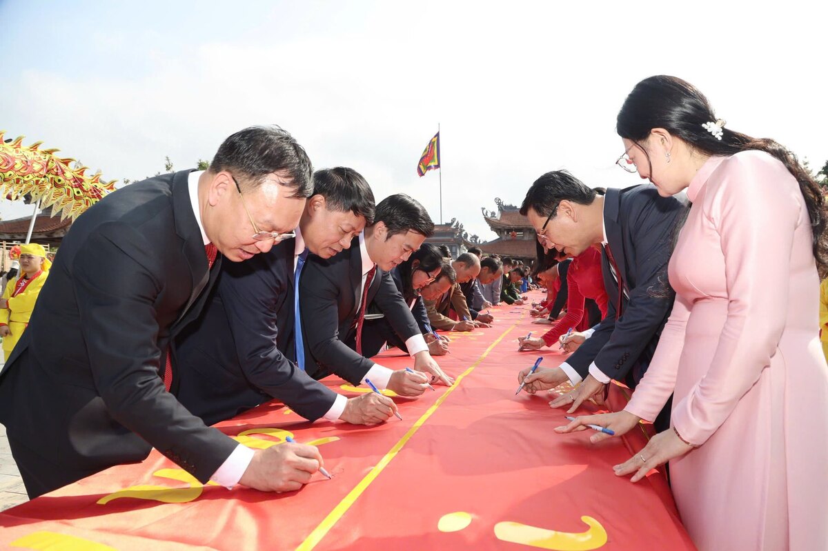 Delegates and people perform the calligraphy opening ceremony on a 65m long silk ribbon. Photo: Viet Cuong