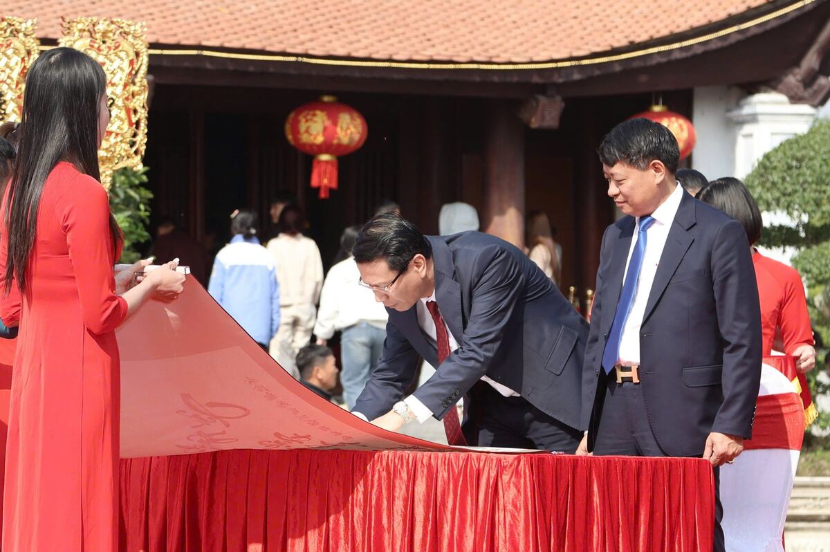 Các đại biểu khai bút đầu xuân trên dải lụa 65m. Ảnh: Việt Cường