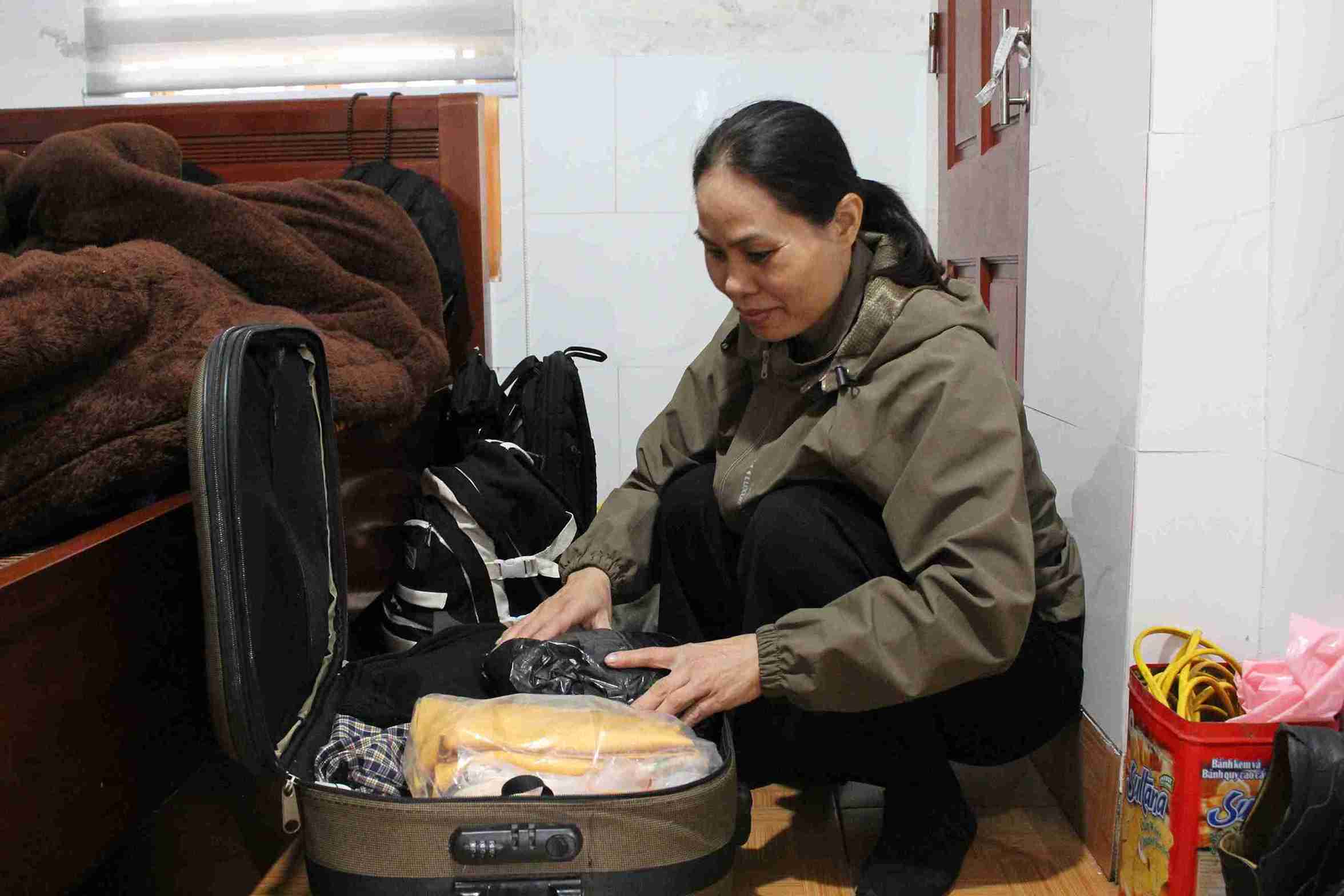 Chị Đào Thị Thinh ngồi xếp quần áo trong buổi sáng rời quê. Ảnh: Mai Hương  