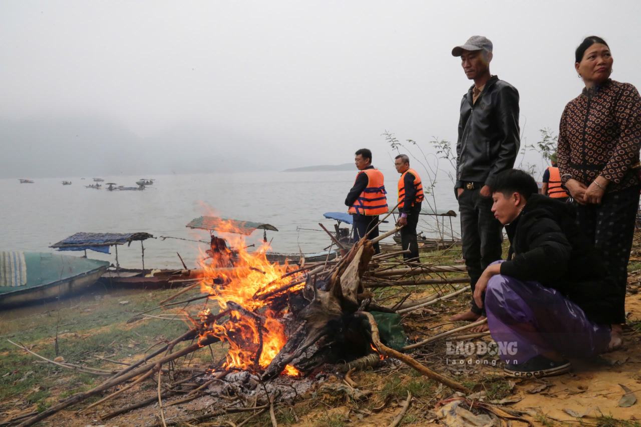 Người dân đốt lửa sưởi ấm cho các thợ lặn sau khi lên bờ. Ảnh: Văn Đức