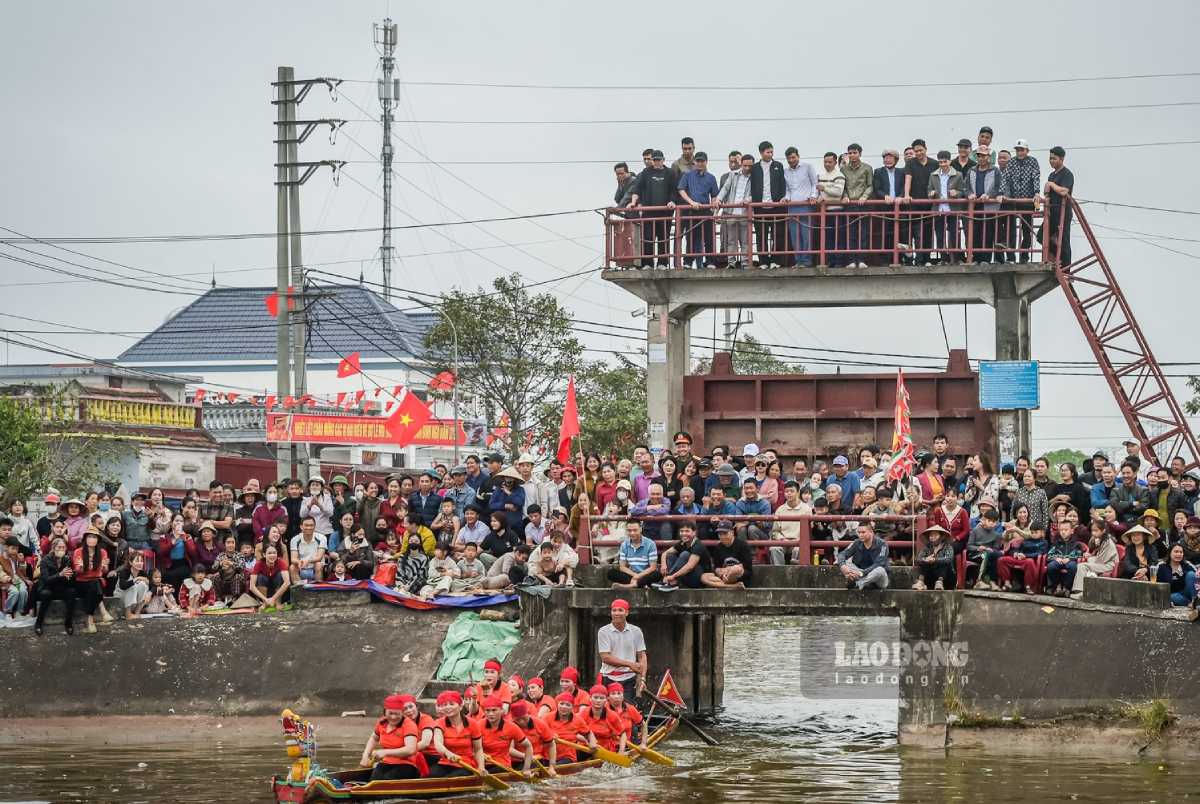 Người dân ngồi đông kín bờ sông xem đua bơi chải đầu xuân. Ảnh: Hà Vi
