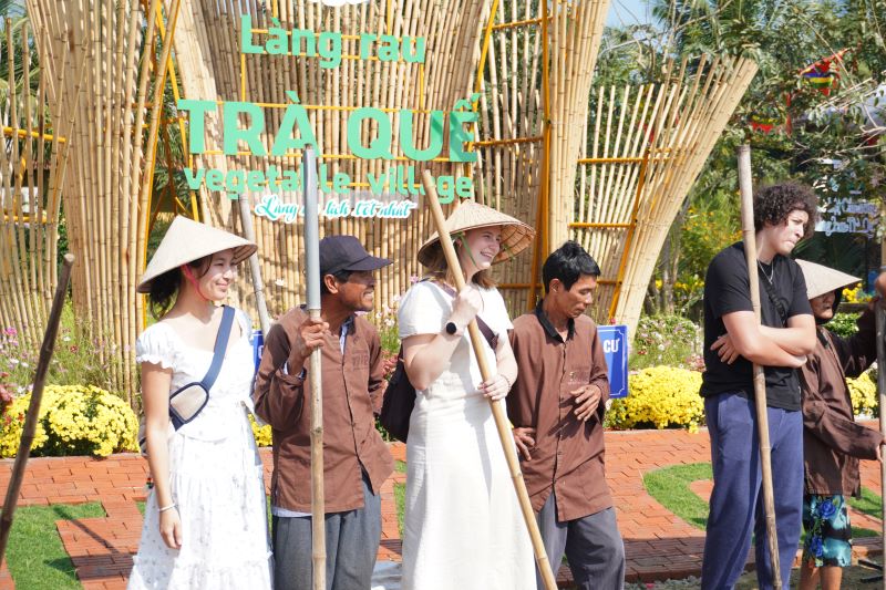 Du khách tham gia cùng người dân bón rau, tưới nước tại Làng rau Trà Quế. Ảnh: Trần Thi