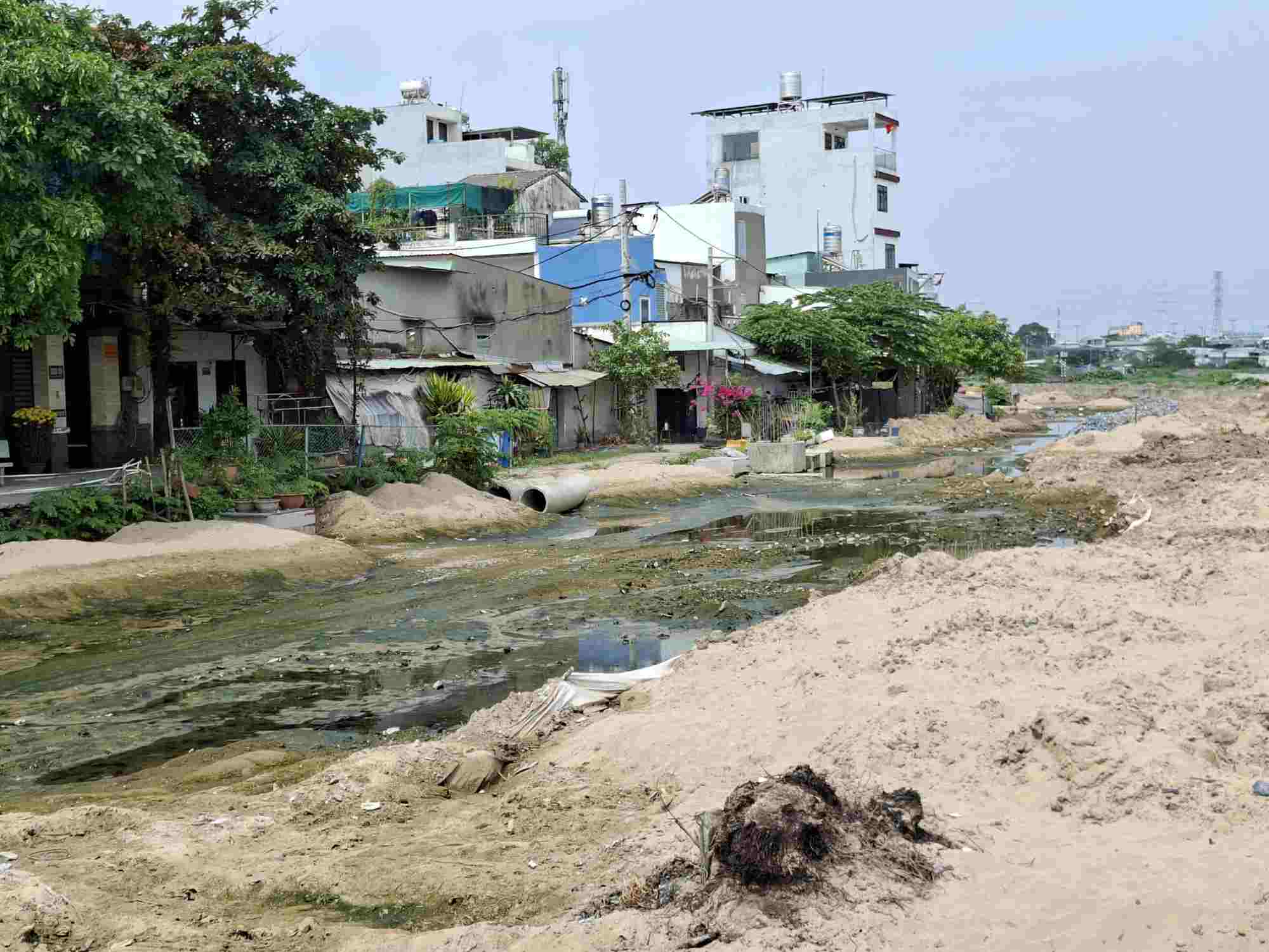Đoạn đường ven kênh thi công dang dở, đọng nước gây ô nhiễm. Ảnh: Minh Quân