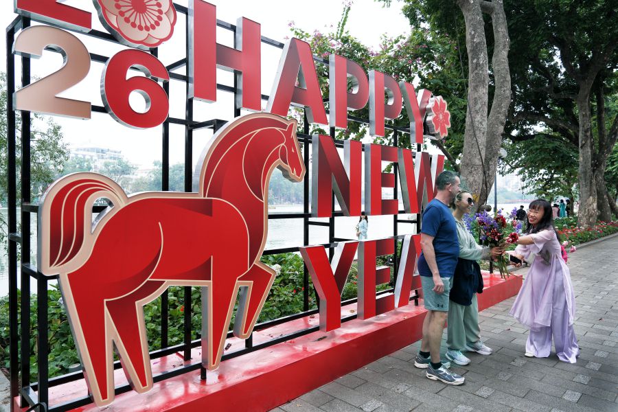 Cô gái cho hai du khách nước ngoài mượn hoa để chụp ảnh lưu niệm. Ảnh: Việt Văn