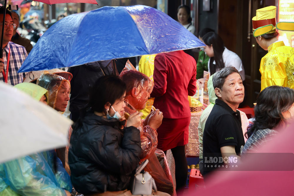 Nhiều người chủ động trang bị ô, áo mưa, kiên nhẫn bám trụ trước cửa hàng để không mất lượt.