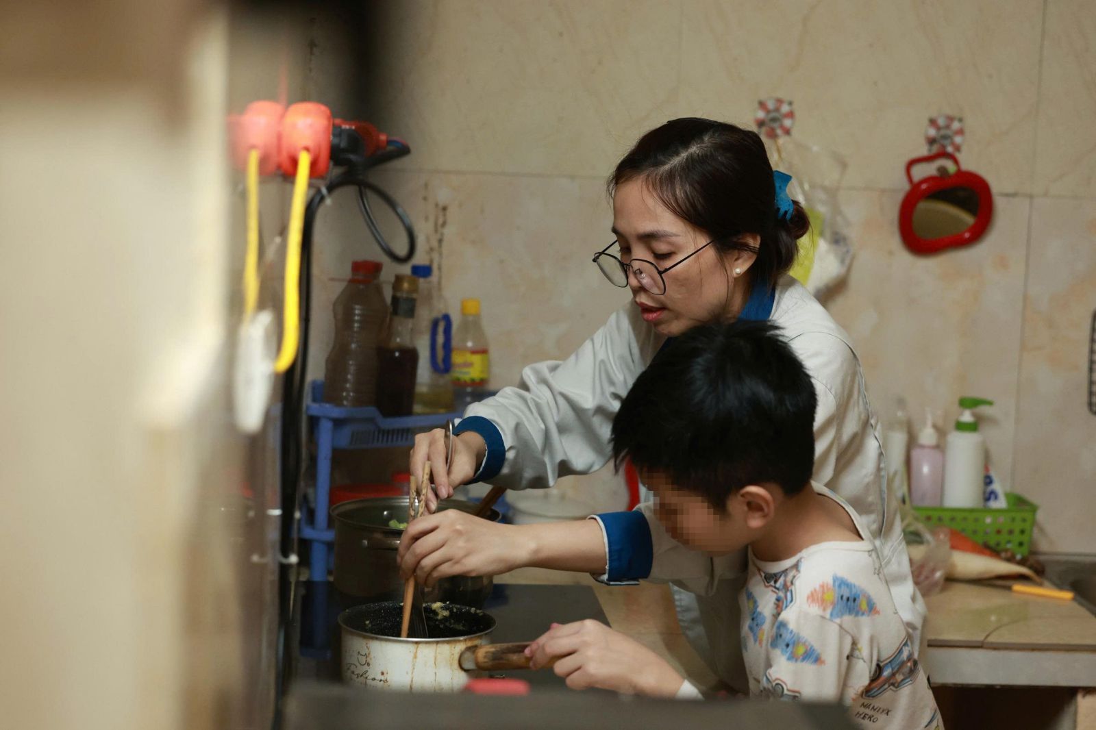 Chị Nguyễn Thị Ngọc Ánh nấu ăn trong bếp của khu nhà trọ. Ước mơ của chị là mua được nhà ở xã hội để có căn bếp rộng hơn. Ảnh: Hải Nguyễn 