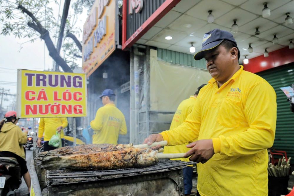 Grillers have to take turns working continuously to ensure the quality of the fish when delivered to customers on the God of Wealth Day. Photo: Anh Tu