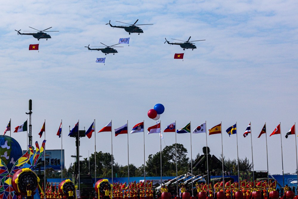 Helicopters carrying national flags and exhibition flags fly over the stands to welcome the Vietnam International Defense Exhibition 2024. Photo: Hai Nguyen