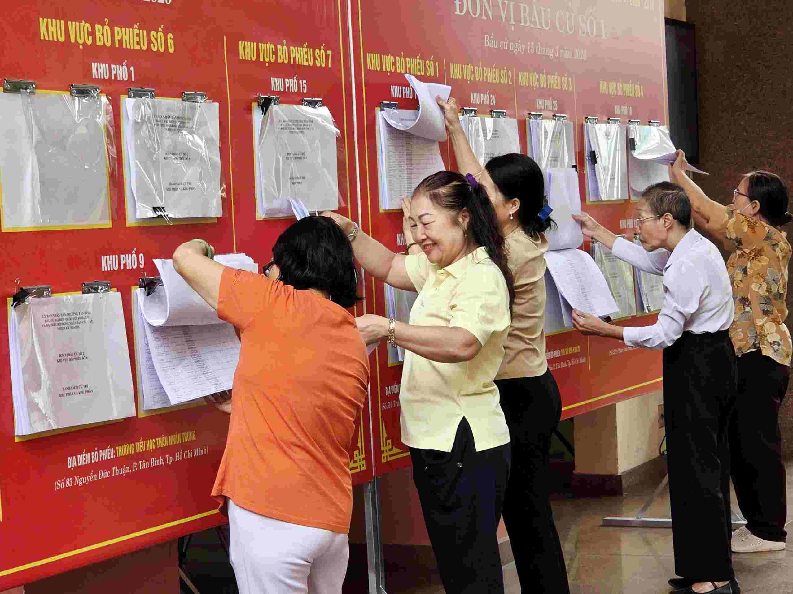 Tranh thủ đi họp, đến giao dịch hành chính, người dân dò danh sách cử tri tại phường Tân Bình. Ảnh: Minh Tâm