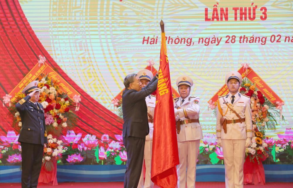 Tổng Bí thư Tô Lâm gắn Huy hiệu danh hiệu Anh hùng Lực lượng vũ trang nhân dân lên Quân kỳ quyết thắng. Ảnh: Quân chủng Hải quân