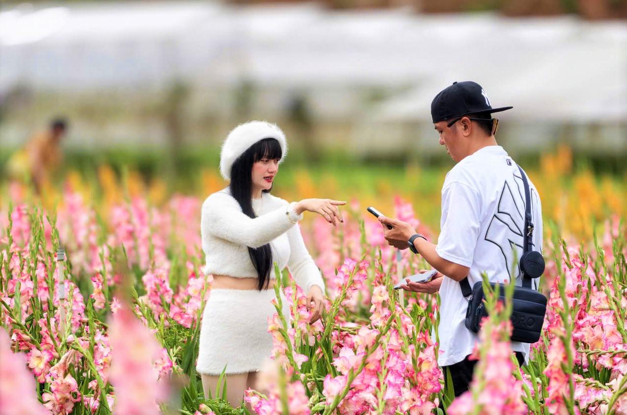 Đôi bạn trẻ tham quan, chụp hình ghi lại những khoảnh khắc ấn tượng bên vườn hoa lay ơn. Ảnh: Phúc Khánh 