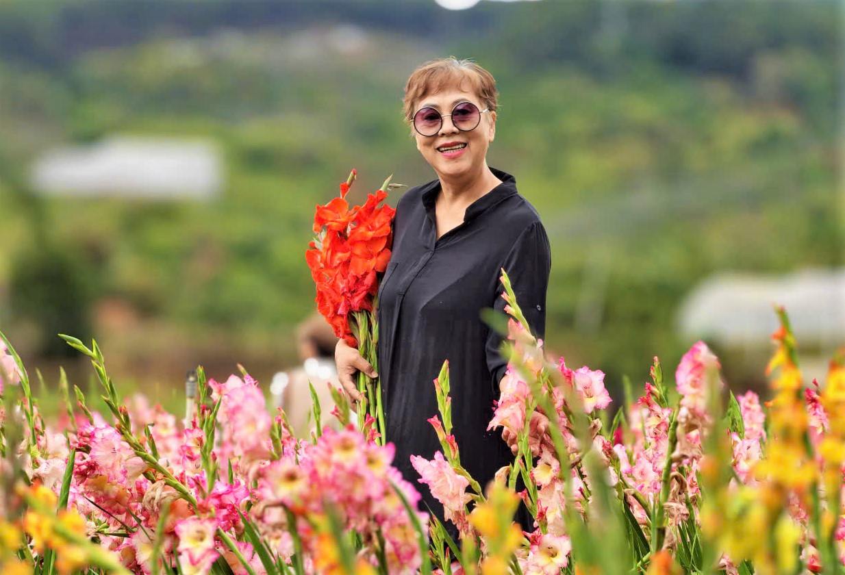 Một nữ du khách vui tươi ghi lại hình ảnh bên vườn hoa lay ơn khi đến Đà Lạt. Ảnh: Phúc Khánh 