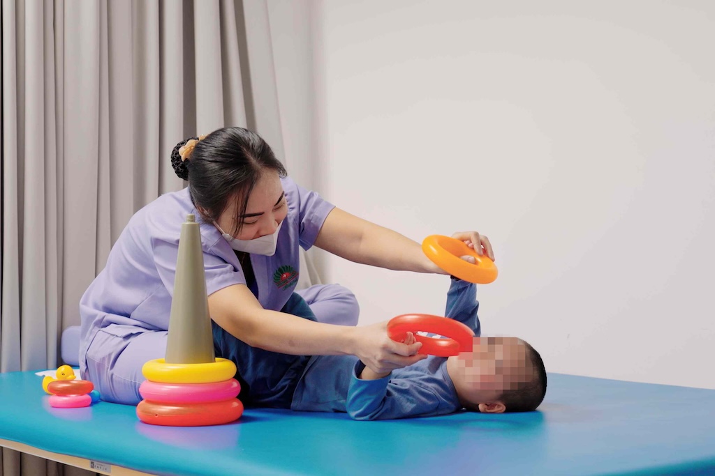 Em bé tập vật lý trị liệu cùng kỹ thuật viên. Ảnh: BVCC