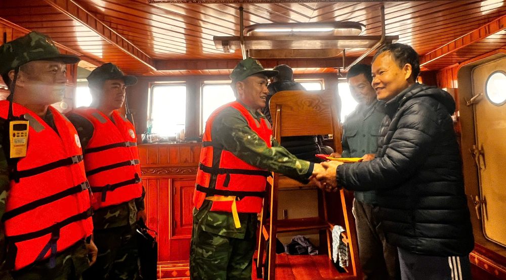 Trung tá Vũ Văn Hiếu trao tặng cờ Tổ quốc cho ngư dân, động viên bà con yên tâm vươn khơi, bám biển. Ảnh: Bình Minh 