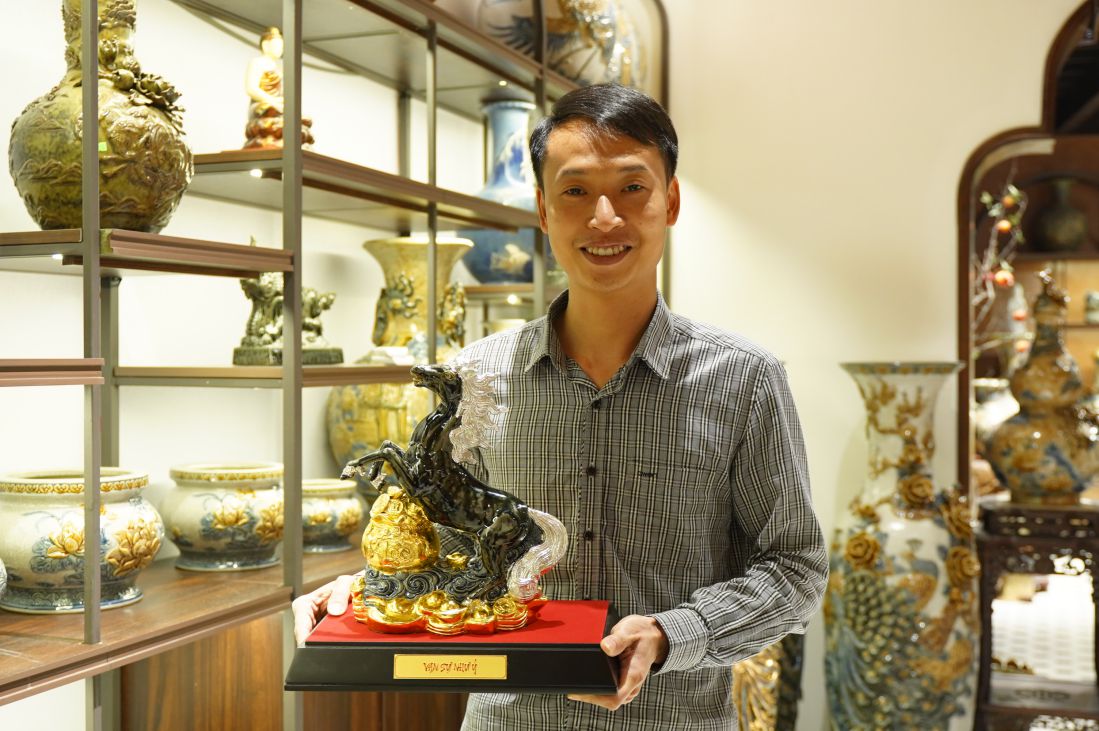 Artisan Nguyen Trong Nghia in the pottery display space, next to finished products. Photo: Trang Anh