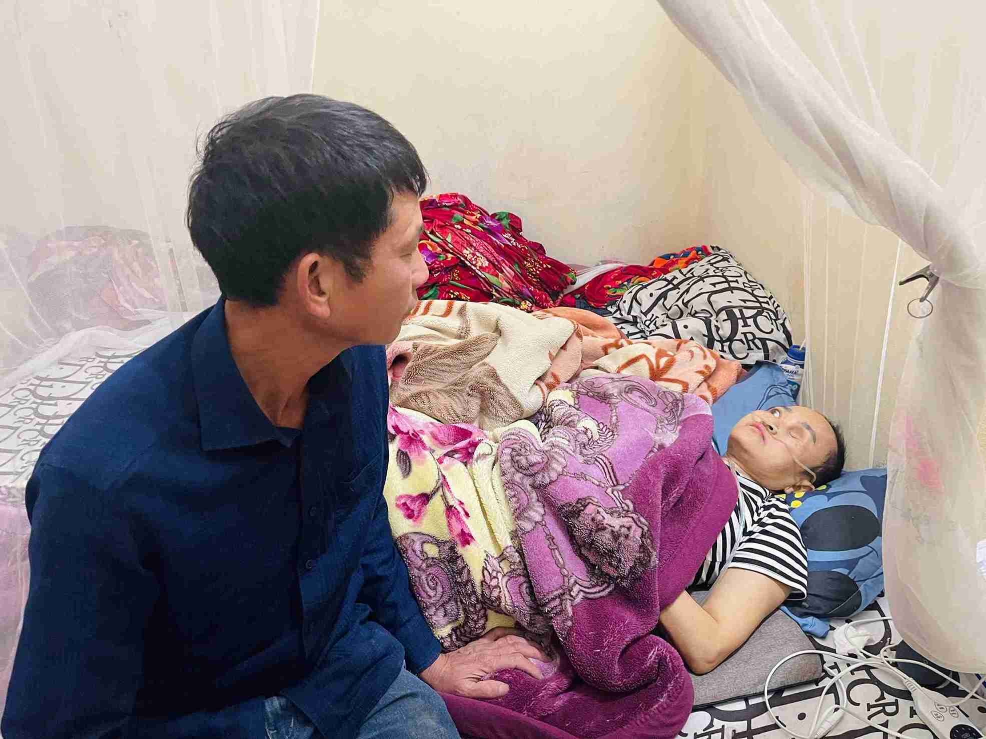 Mr. Nguyen Binh Thao sitting next to his wife's bed. Photo: Mai Huong