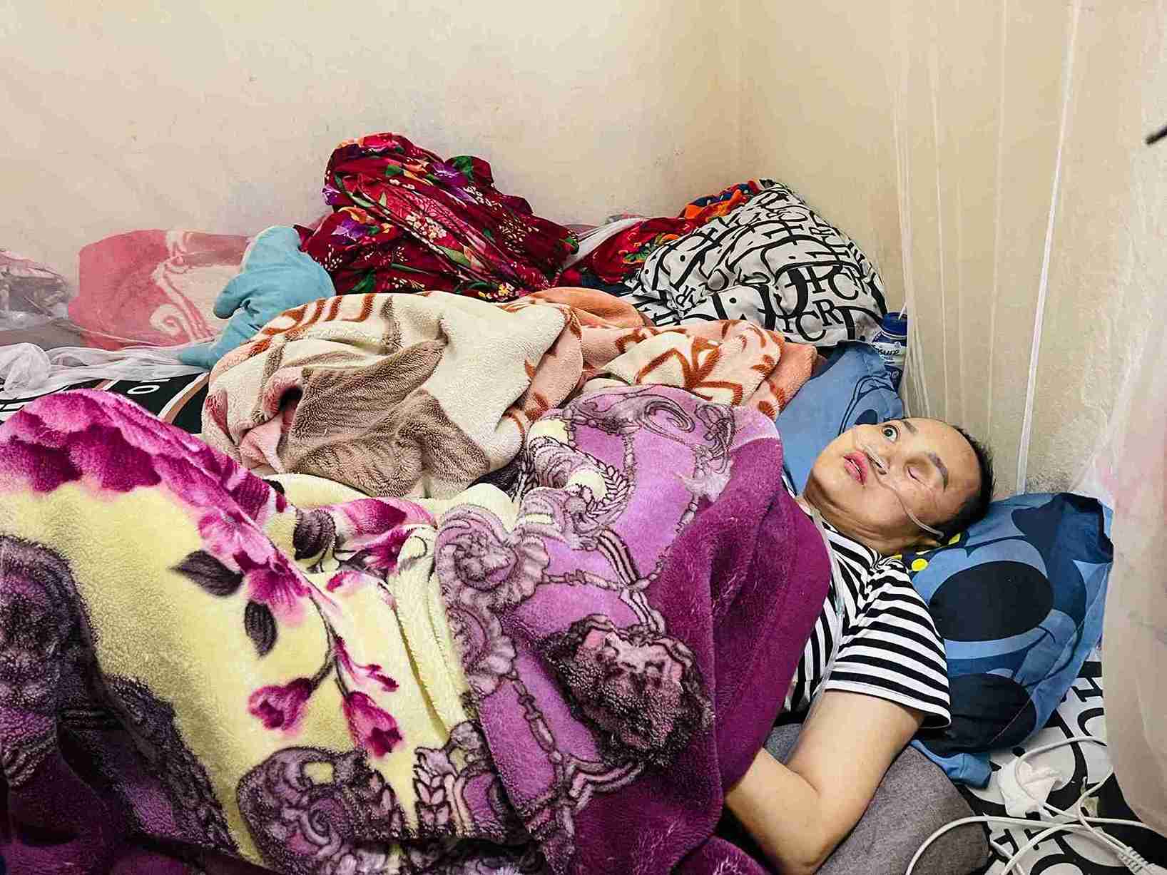 Chị Đàm Thị Thu hiện phải nằm một chỗ, sức khỏe suy kiệt sau thời gian điều trị bệnh. Ảnh: Mai Hương