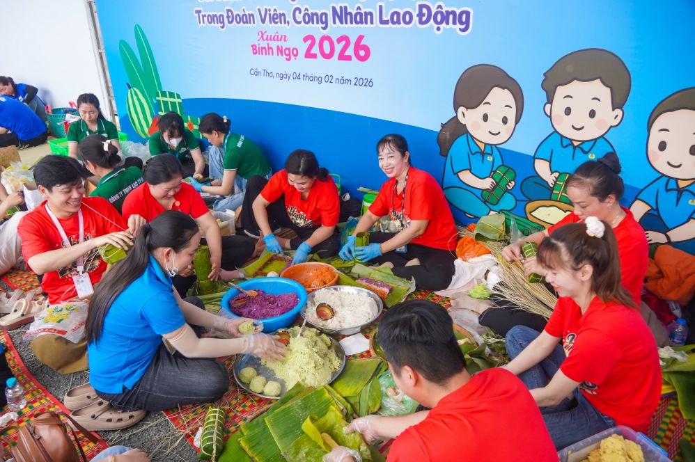 Trade union members happily gather together to wrap banh tet cakes. Photo: Ta Quang