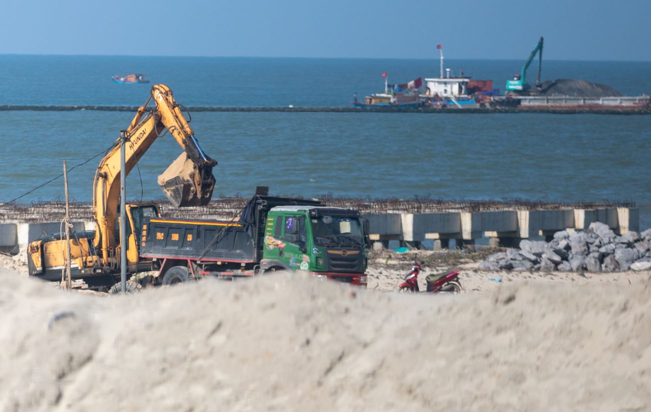 Máy xúc màu vàng của CFG Quảng Trị đưa cát lên xe ôtô tải để vận chuyển ra ngoài dự án tiêu thụ. Ảnh: Hưng Thơ