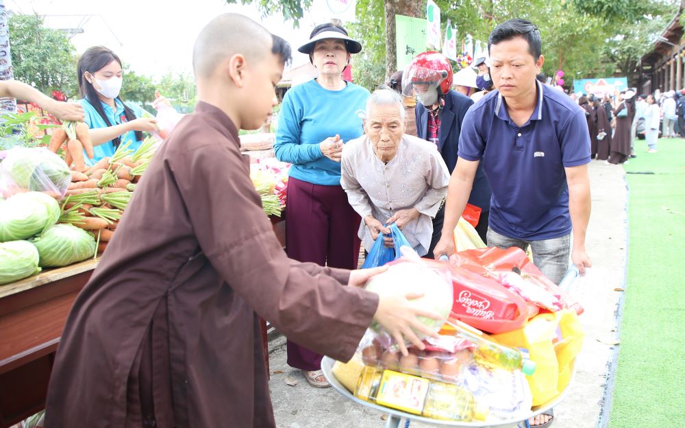Người tàn tật, người già được hỗ trợ đẩy xe nhận hàng ở phiên chợ. Trong ảnh, bà Lê Thị Lý (93 tuổi, thôn Nhan Biều, xã Triệu Phong) được nhận 40 phần quà. “Tết này không phải mua sắm chi cả, đầy đủ rồi” - bà Lý nói. Ảnh: Hưng Thơ