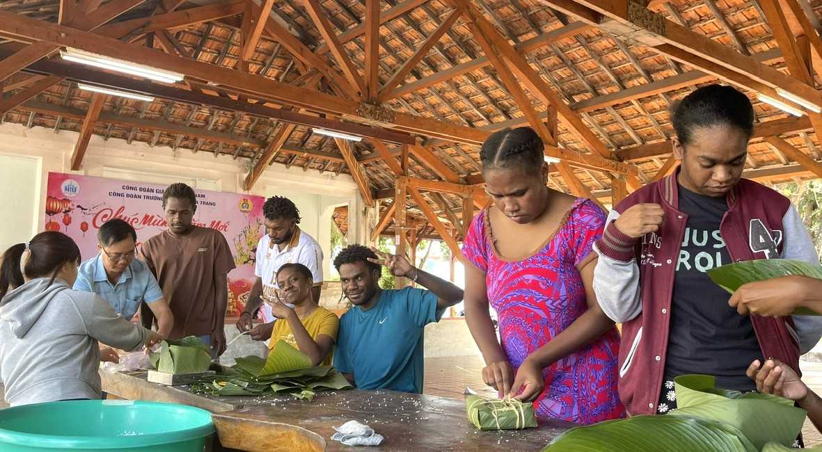 Các em sinh viên quốc tế cùng tham gia học gói bánh chưng với thầy cô để đón Tết Việt. Ảnh: Trọng Đạo