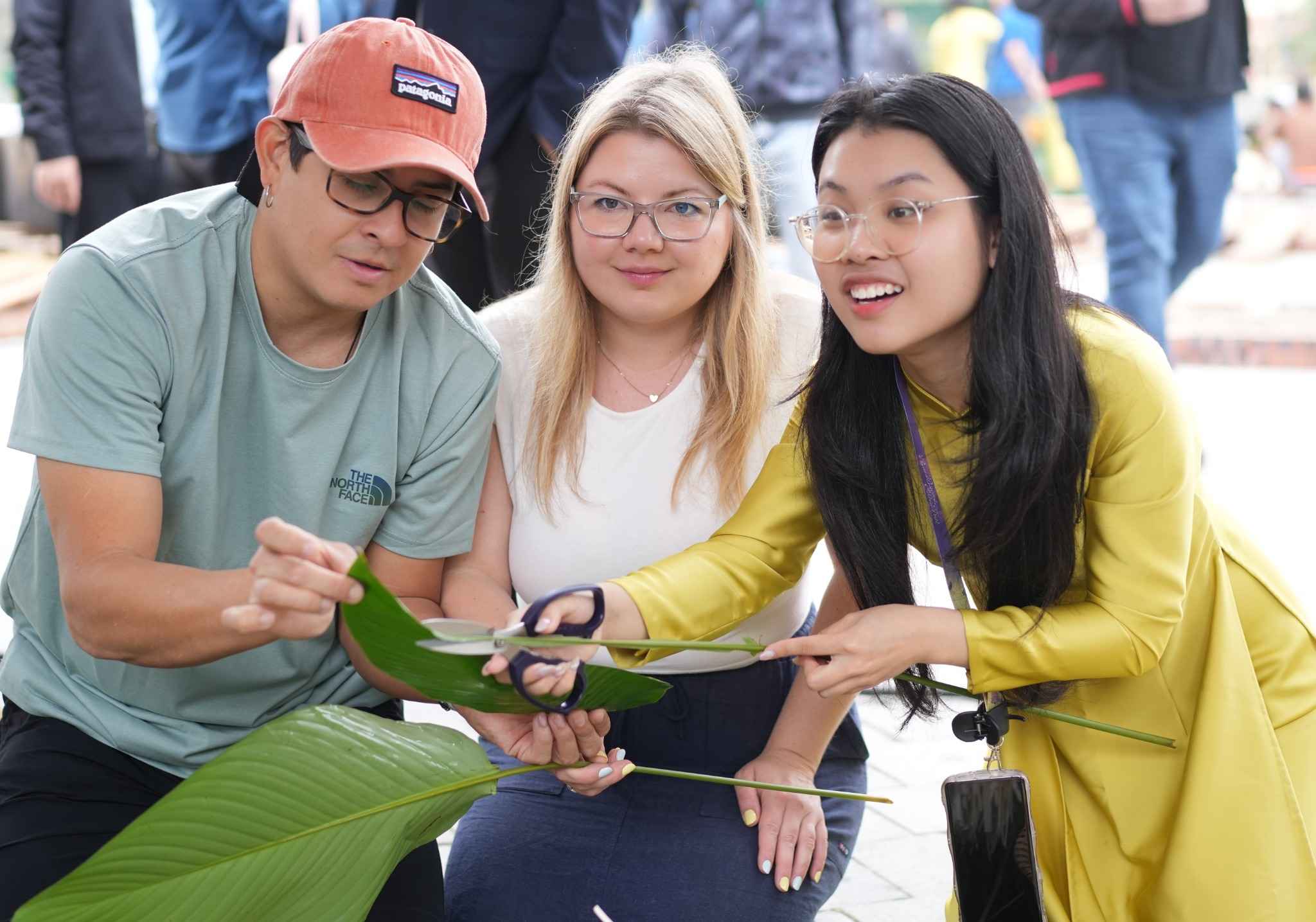 Người dân địa phương hướng dẫn du khách nước ngoài gói bánh chưng. Ảnh: Diệu Anh