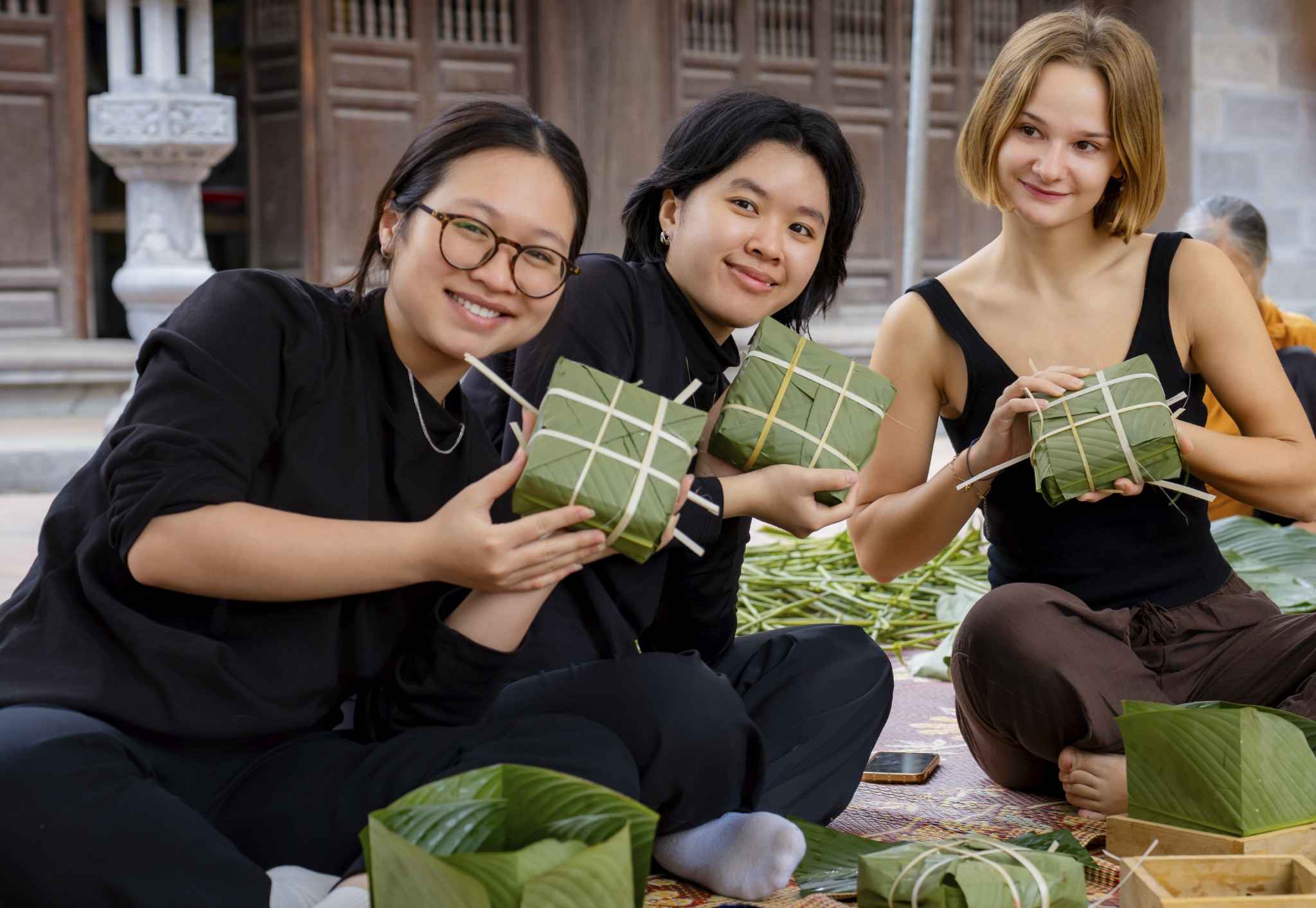 Du khách nước ngoài thích thú khi được tham gia gói bánh chưng. Ảnh: Diệu Anh