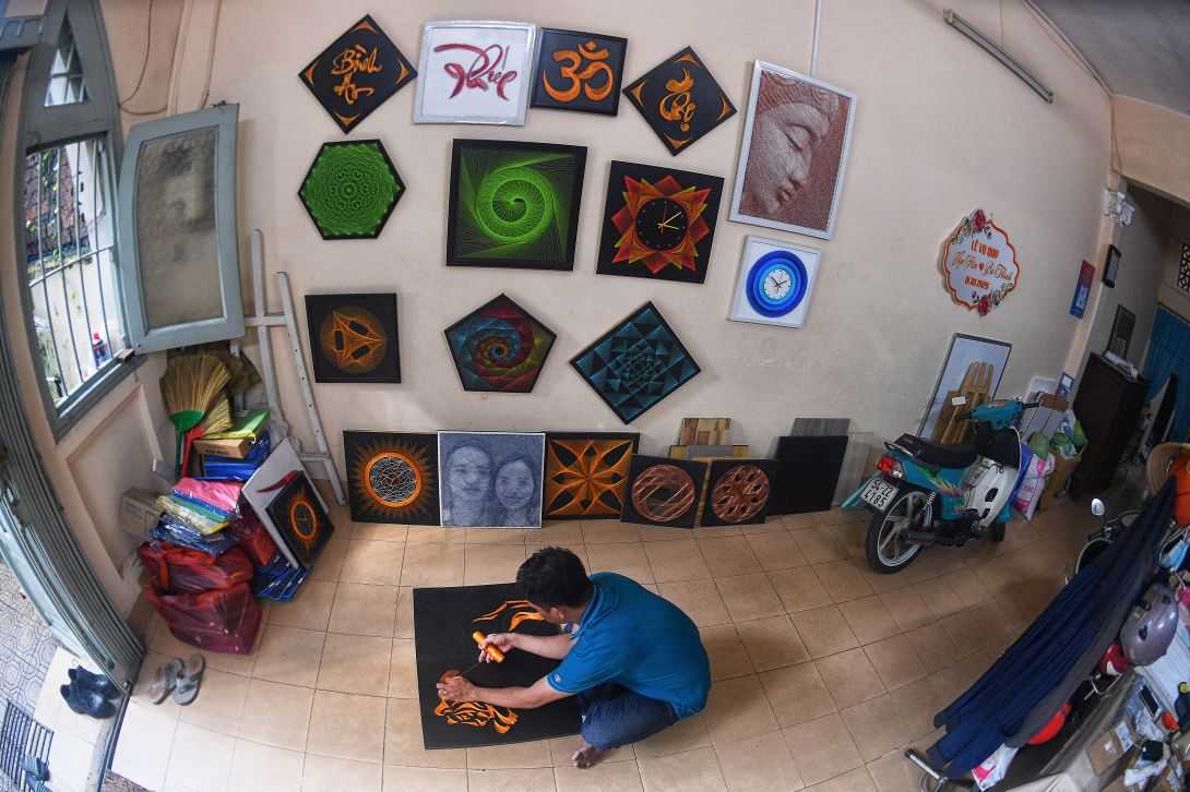 Nghệ nhân Phan Bá Thành làm tranh đinh chỉ. Ảnh: Việt Văn