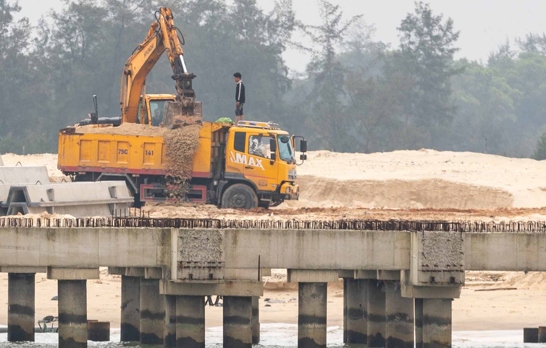 Cát trong dự án CFG Nam Cửa Việt được máy xúc lên xe tải, sau đó xe di chuyển ra ngoài đưa đi tiêu thụ. Ảnh: Hưng Thơ