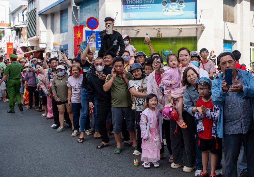  Người lớn và trẻ em ra đường để được tận mắt ngắm nhìn đoàn diễu hành đi qua. Nhiều người dân tại khu vực Chợ Lớn hân hoan đón chào đoàn rước kiệu Ông, tạo nên một bầu không khí nhộn nhịp trước thềm Tết Nguyên Tiêu.