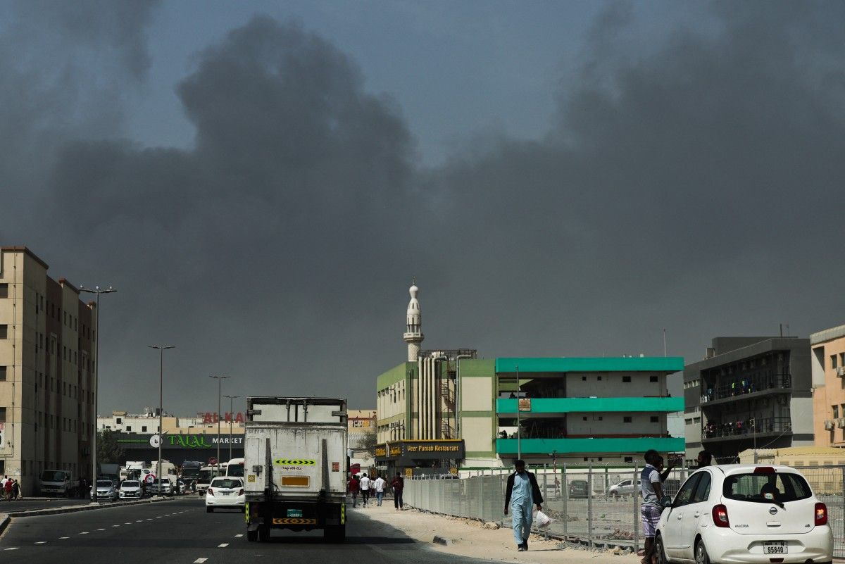 People walk near the area where thick smoke rises from the location hit by Iran's attack in Dubai on March 1, 2026. Photo: AFP