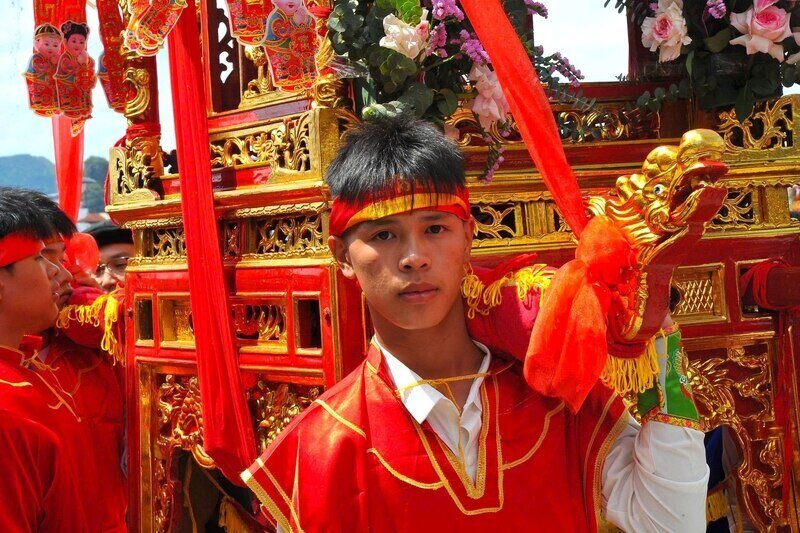 Hàng chục thanh niên trong trang phục đỏ rực truyền thống cùng nhau khiêng kiệu trong tiếng trống hội, tiếng reo hò náo nhiệt của người dân.