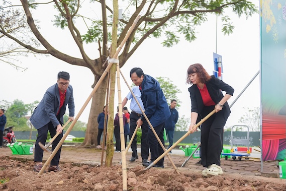 Mme Nguyễn Thị Đào - Présidente du syndicat de la société générale May 10 (à l'extrême droite) participe à la plantation de 80 arbres de fleurs de ban sur la rue Trần Danh Tuyên, quartier de Phúc Lợi, Hanoï. Photo: CĐM10