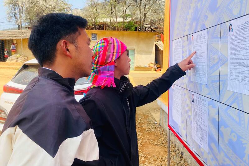 Cử tri bản Nậm Nghẹp, xã Ngọc Chiến theo dõi bảng niêm yết danh sách và tiểu sử tóm tắt của ứng cử viên. Ảnh: Trường Sơn