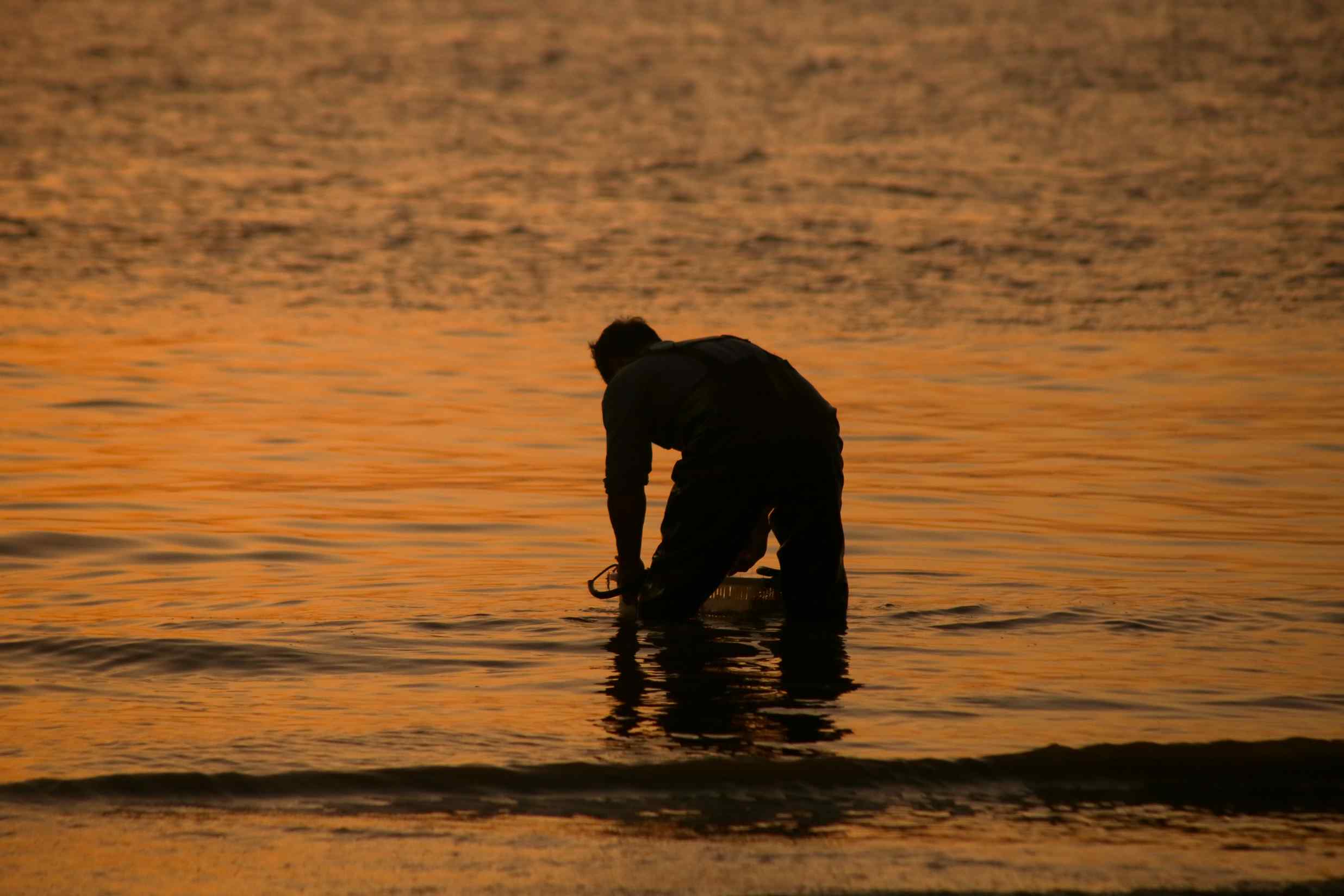 แสงตะวันยามเย็นสาดส่องลงบนผืนน้ำ สะท้อนและระยิบระยับบนคลื่นลูกเล็ก ๆ สร้างภาพอันสงบสุขอันเป็นเอกลักษณ์ของหมู่บ้านริมทะเล