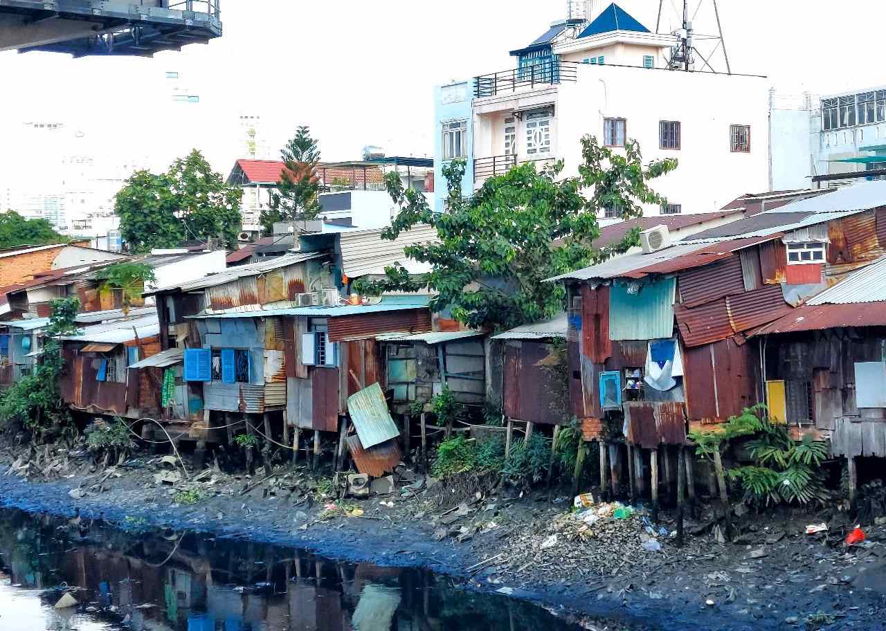 Dilapidated rows of houses with corrugated iron roofs and leaning piles along Van Thanh canal (HCMC). Photo: Minh Quan